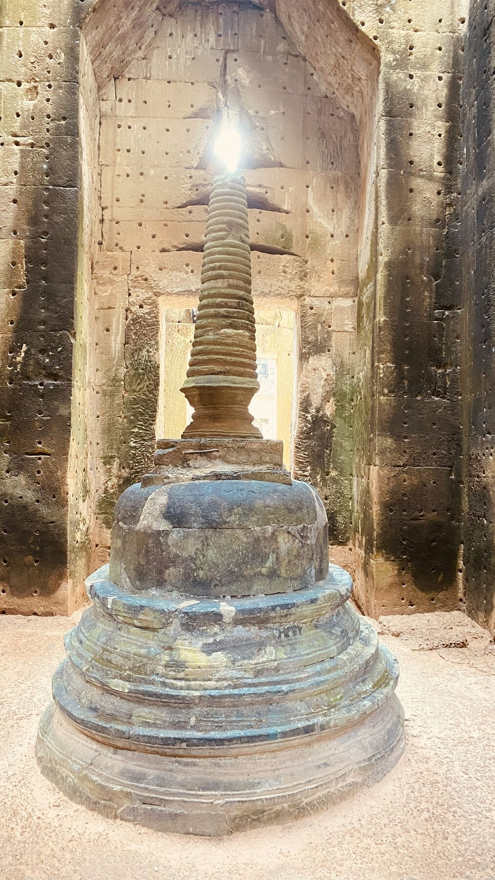 Stone stupa lit by a shaft of sunlight inside a temple