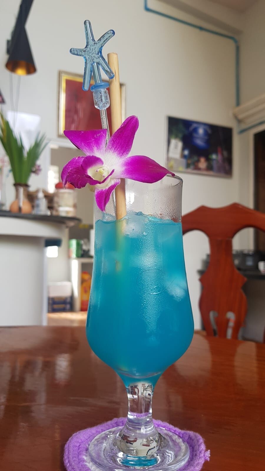 Blue cocktail garnished with an orchid